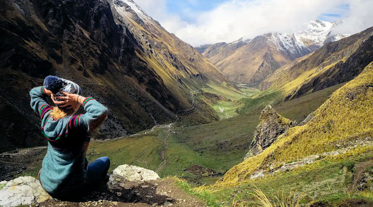 Viajera sentada contemplando la vista de Salkantay, uno de los maravillosos tours de aventura en Perú