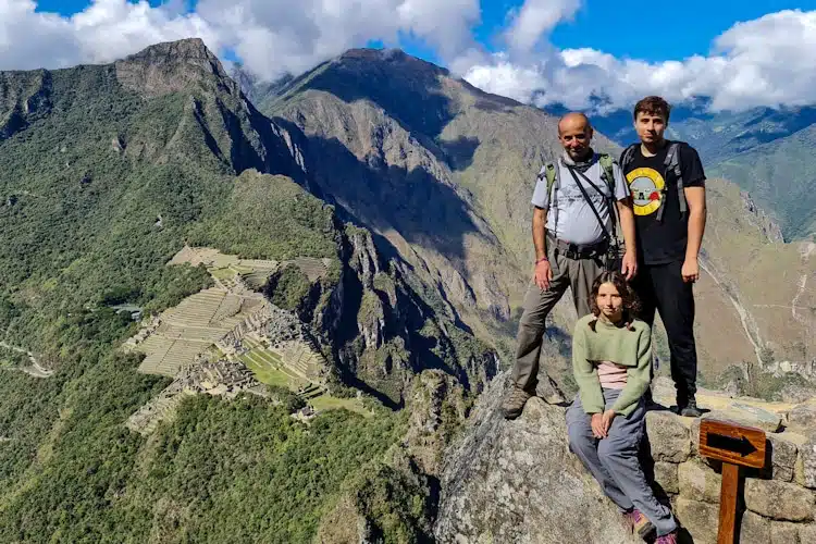 Fertur Peru client and his children stand atop Huayna Picchu overlooking Machu Picchu