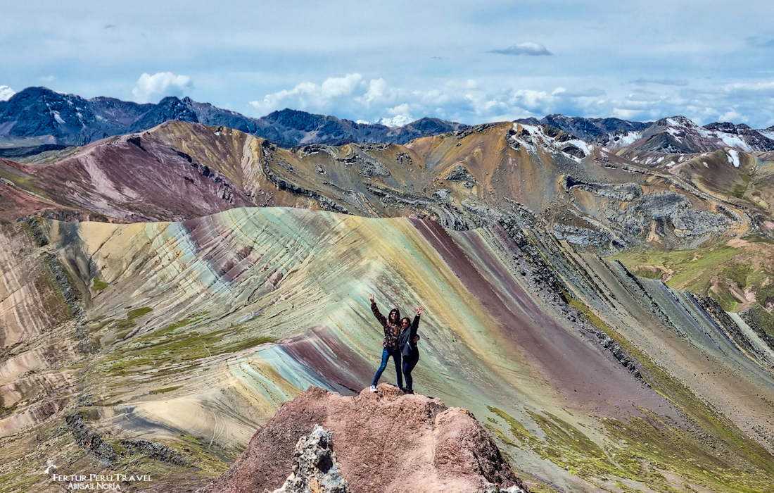 Travelers pose at the summit of the Palcoyo Rainbow Mountain