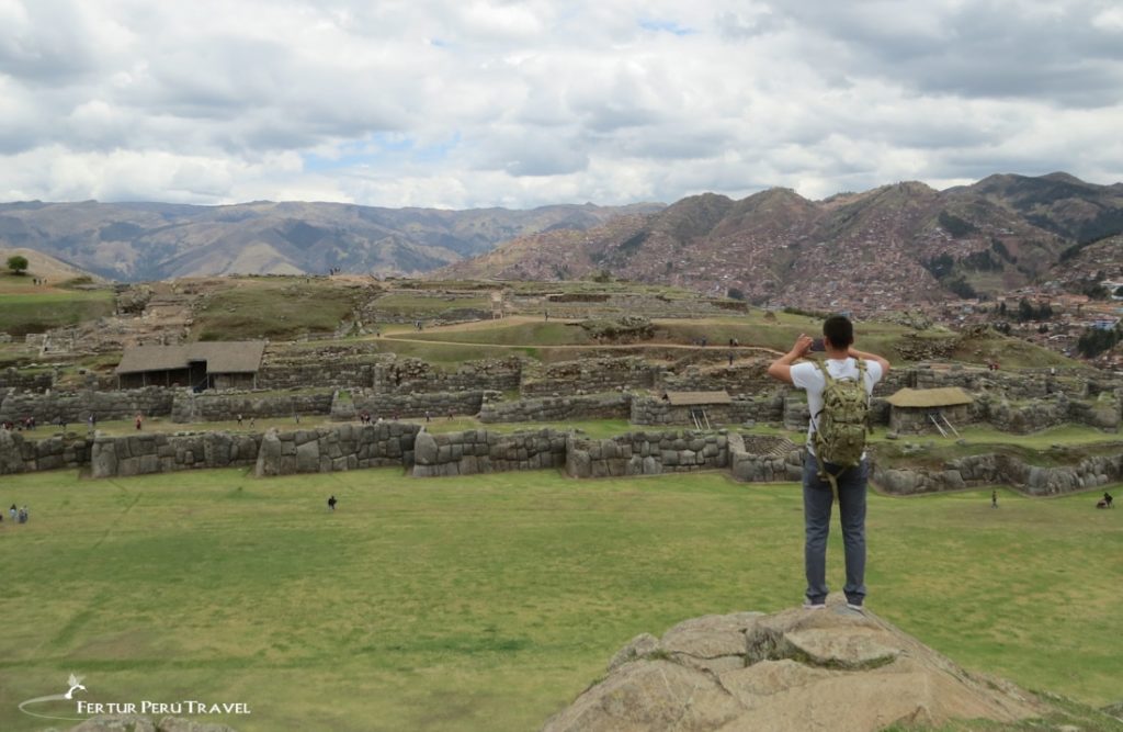 Un viajero parado en lo alto de un acantilado para tener una visión general del magnífico Templo Fortaleza Inca de Sacsayhuaman - Cusco Tours con Fertur Perú Travel