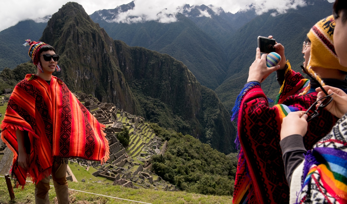 Travelers taking the iconic photo at Machu Picchu with Huayna Picchu in the background — the culmination of their 14 day Peru itinerary